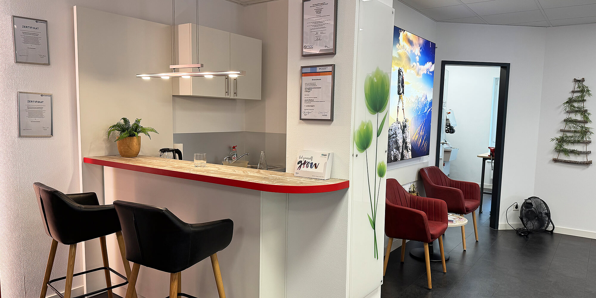 Wartebereich mit roten Sesseln, Beistelltisch und Blick in angrenzende Räume